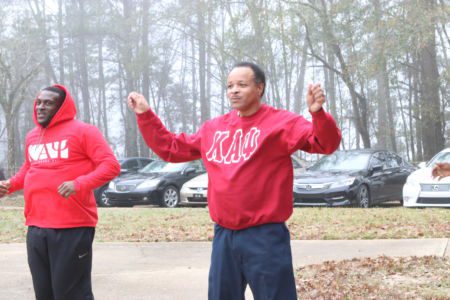 Two men in red shirts are standing outside.